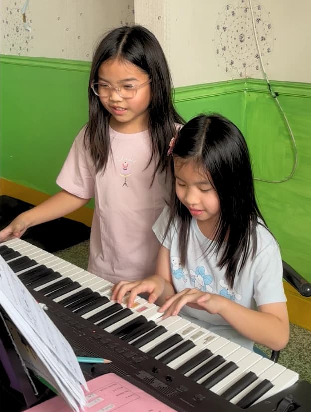 Two students learning to play the piano